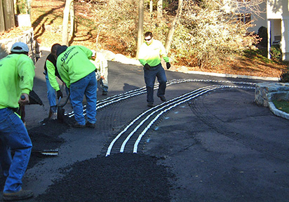 Asphalt heated driveway with heated tire tracks being installed.